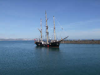 A Weymouth tall ship in Weymouth harbour with the stone pier in the background. 